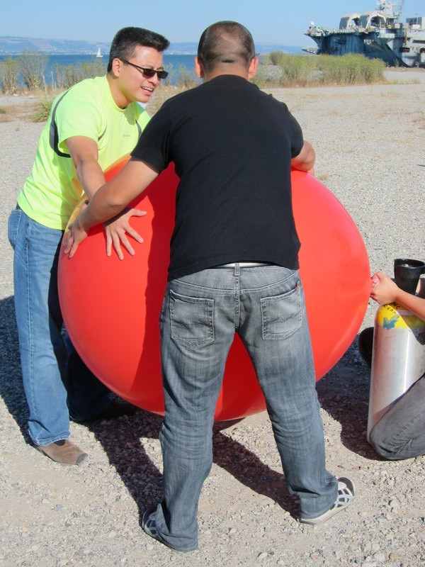 Simon and Patrick brace the Big Red Balloon while it is inflating.