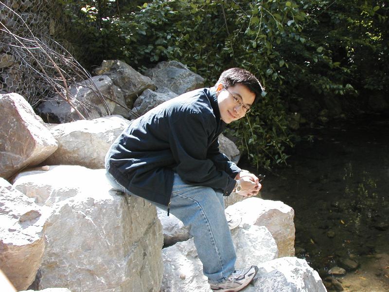 Simon sits on some rocks at the side of the creek