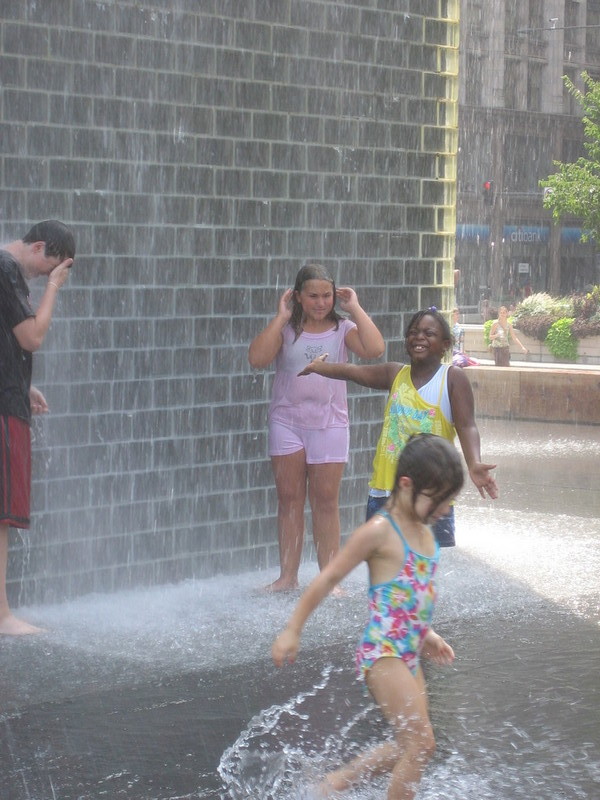 Kids splashing and having fun at the "faces" sculptured fountain